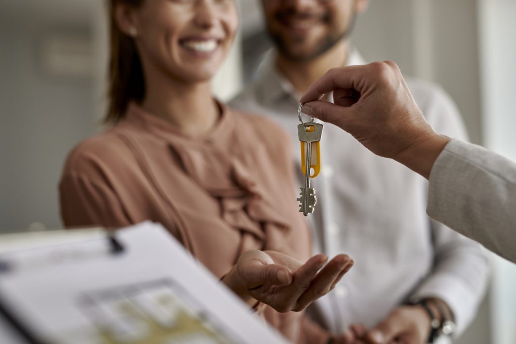 Close-up of couple receiving new house keys from real estate agent