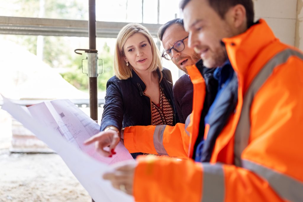 Design & Construct Male architect showing new apartment construction blueprints to a couple